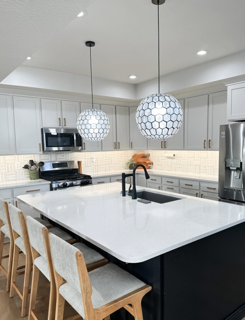 The "after" of our kitchen makeover shows our gray and white tile backsplash, globe light fixtures, and under-counter lighting! This no demo reno was a success. 